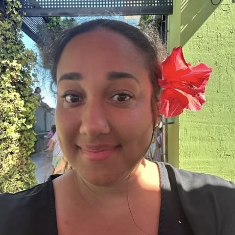 Erica smiling, with a red hibiscus flower in her hair